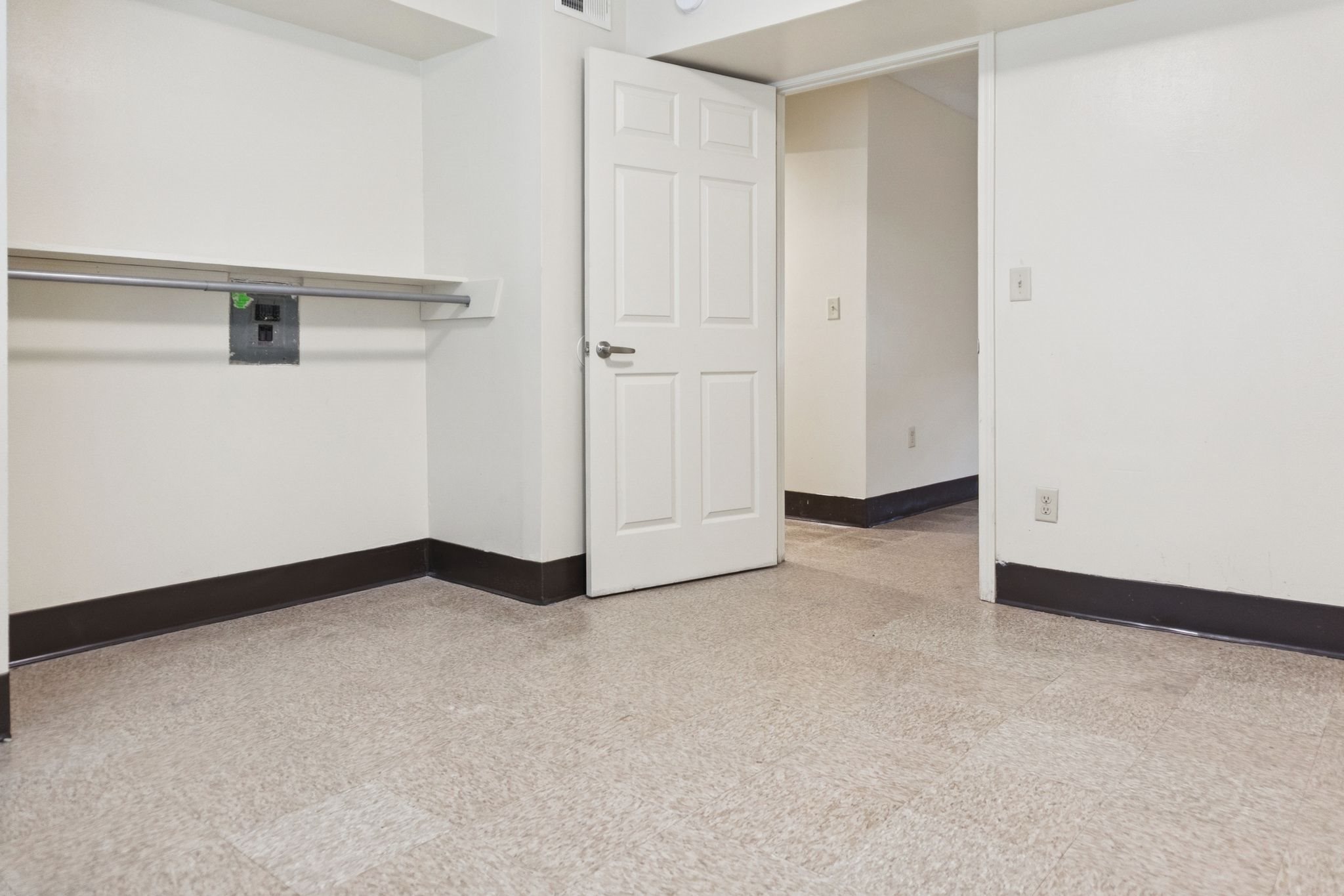 A white door is in a hallway with a tiled floor.